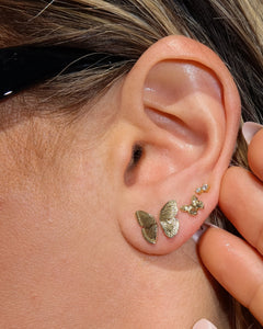 Girl with piercings wearing dainty gold butterfly earrings and cubic zirconia stud earrings that are hypoallergenic and nickel free
